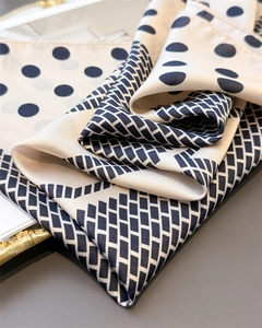Detail of silk satin scarf featuring elegant black polka dots and geometric grid patterns