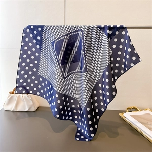 Detail of navy blue polka dot silk scarf hanging with smooth draping and soft texture