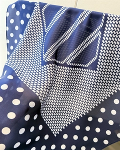 Detail view of navy blue polka dot silk scarf showing thin fabric texture and geometric prints