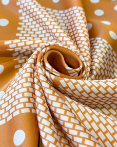 Macro detail of silk-like scarf with caramel orange polka dots and geometric patterns