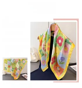Dettaglio di un elegante foulard in seta floreale con bordo giallo e trama liscia