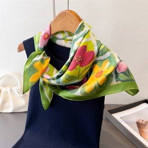 Dettaglio di un foulard di seta a fiori dipinti a olio su un elegante top in maglia nera