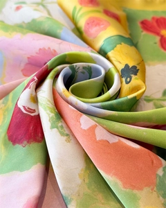 Macro di un foulard in raso a fiori colorati con pieghe a spirale e consistenza setosa