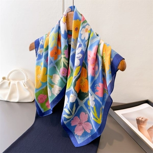 Foulard quadrato in seta azzurro con stampa floreale a olio appeso a una gruccia in legno