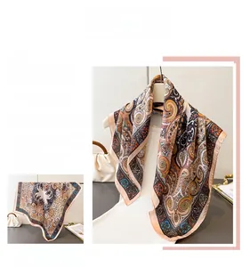 Detail of vintage paisley silk scarf featuring warm orange and navy blue patterns