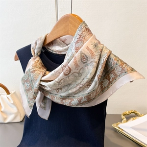 Detail of elegant paisley silk scarf tied on a black top showcasing drape and texture