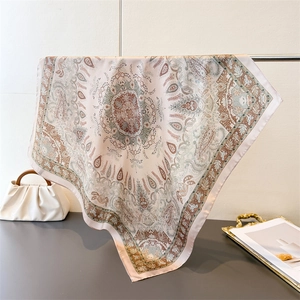 Detail of elegant paisley silk-like square scarf draped on a rack for a luxury feel