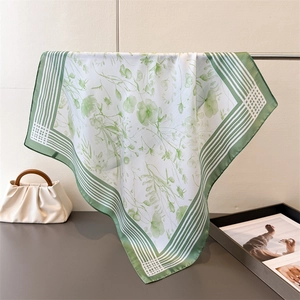 Detailed drape of a premium silk scarf featuring watercolor green floral prints and stripes