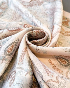 Close-up of elegant paisley pattern on soft beige silk scarf showing fabric texture