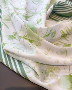 Macro shot of white silk scarf with green floral prints and smooth draped texture