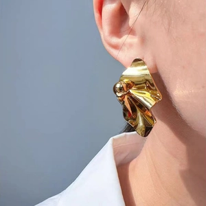 Chic irregular crumpled metal drop earrings in gold finish worn by a model