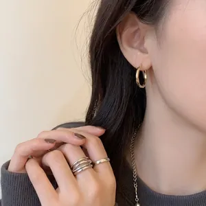 Eleganti orecchini a cerchio intrecciati dorati indossati da una modella stile minimal