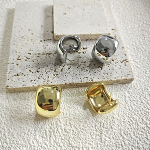 Close-up of chunky gold and silver hoop earrings with a high-polished mirror finish