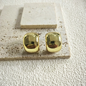 Macro shot of chunky gold geometric hoop earrings with polished mirror finish surface