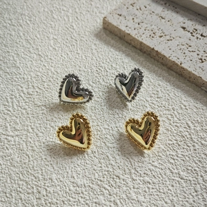 Polished heart-shaped stud earrings in gold and silver with beaded edge detailing