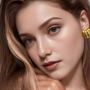Détail d'une femme portant des boucles d'oreilles créoles dorées style croissant