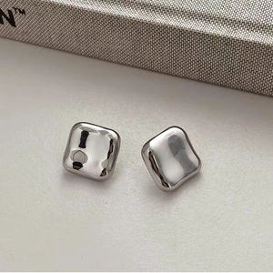 Vue macro de boucles d'oreilles carrées argentées avec texture martelée irrégulière
