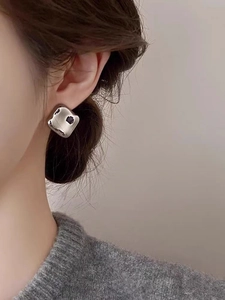 Gros plan de boucles d'oreilles carrées en argent avec texture martelée portées par un mannequin