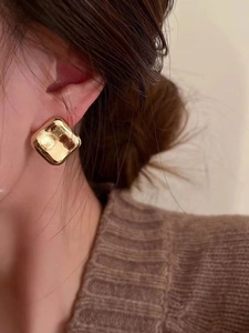 Gros plan de boucles d'oreilles carrées dorées géométriques portées par un mannequin