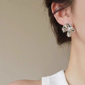 Boucles d'oreilles minimalistes irrégulières argentées sur mannequin au fini texturé