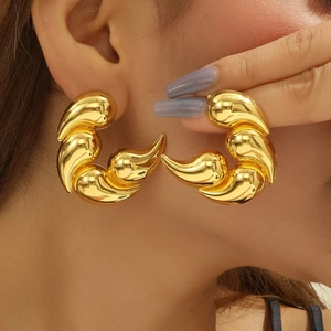 Chic oversized gold teardrop earrings with layered metallic sculptural flame design on model