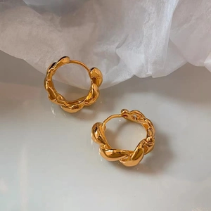Vue macro de boucles d'oreilles créoles torsadées dorées sur papier texturé