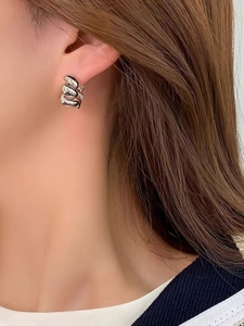 Gros plan de boucles d'oreilles créoles torsadées argentées au fini poli sur mannequin