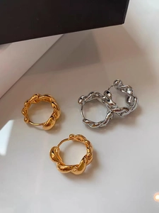 Vue détaillée de créoles torsadées en finitions or et argent polies avec texture corde