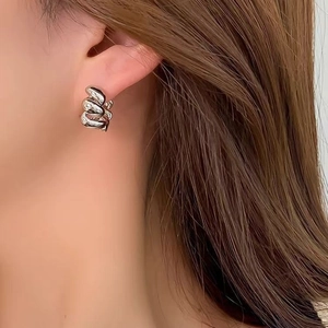 Élégantes créoles torsadées en argent au design tissé portées par un mannequin féminin