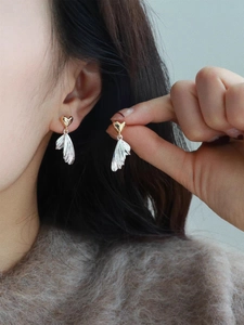 Detail view of stylish two-tone heart and silver feather drop earrings for women