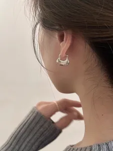 Close-up of polished silver saddle hoop earring with minimalist high-shine mirror finish