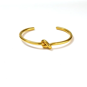 Minimalist golden knot open bangle with a polished mirror finish and adjustable C-shape design