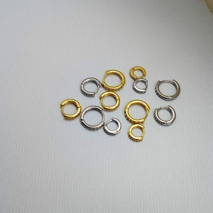 Makro-Detail von goldenen und silbernen S925 Creolen mit funkelnden Zirkonia-Steinen