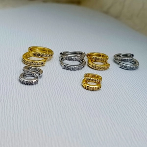 Detail von minimalistischen Huggie-Ohrringen mit weißen Zirkonia in Gold und Silber Optik