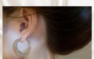 Close-up of elegant gold hoop earrings with pavé crystals worn on a female model