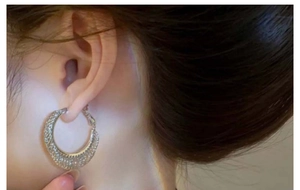 Close-up of silver mesh texture C-shaped hoop earrings worn by a female model