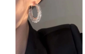 Detail of a large silver hoop earring with glittering finish shown on a model