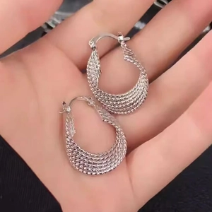 Boucles d'oreilles créoles argentées avec texture entrelacée et design irrégulier