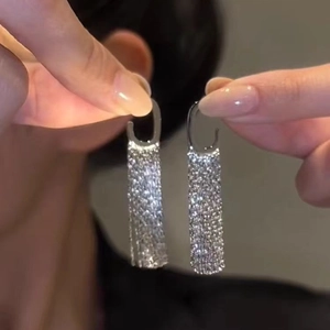 Elegant long silver tassel earrings with sparkling crystals held in hand for display