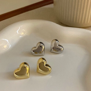 Stereo heart stud earrings in gold and silver finish on a ceramic jewelry tray