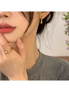Close-up of gold geometric horn earrings and double bead ring worn by a model