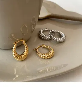 Close-up of geometric horn earrings in gold and silver with twisted metal texture
