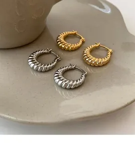 Macro shot of gold and silver croissant twist earrings on a ceramic display tray