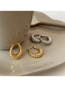 Detailed view of gold and silver croissant twist earrings on a ceramic dish