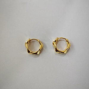 Detailed view of gold twisted hoop earrings with unique wavy texture on white background