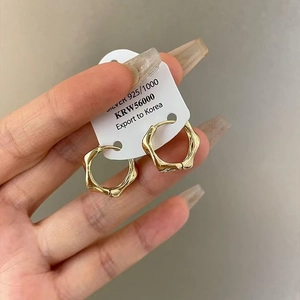 Modern minimalist twisted 925 silver hoop earrings with a shiny gold lava finish