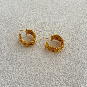 Detailed view of gold plated twisted hoop earrings with textured braided design