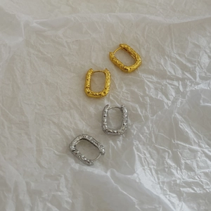 Detail of gold and silver geometric earrings with irregular hammered texture on white paper