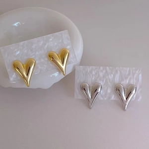 Polished heart stud earrings set in gold and silver finishes on elegant display cards