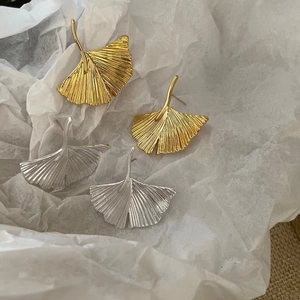 Detailed macro view of ginkgo leaf earrings in gold and silver with textured metal veins